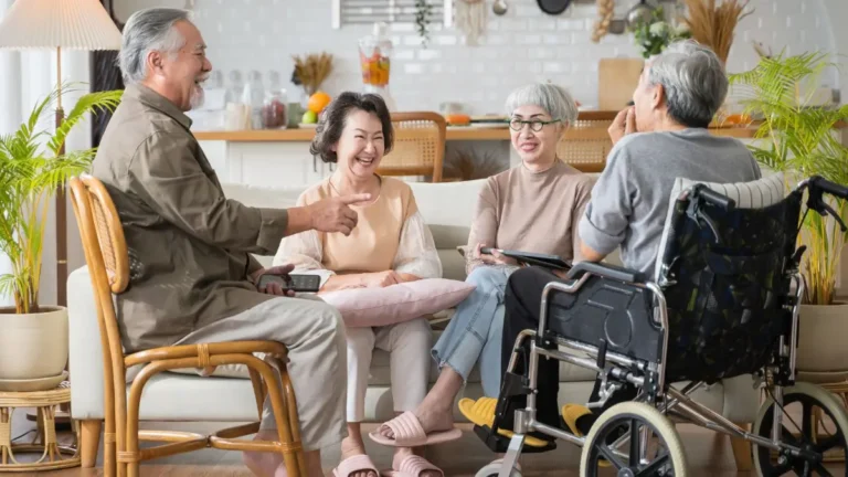 Four seniors laughing in conversation in a senior living apartment